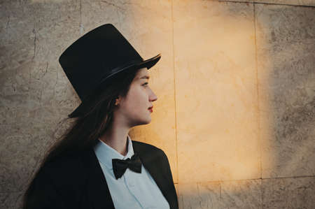 retro portrait in profile of a young girl in a top hat and bow tieの写真素材