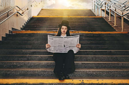 retro portrait of a young girl with a newspaper in her hands. woman standing in a tunnel underpassの写真素材