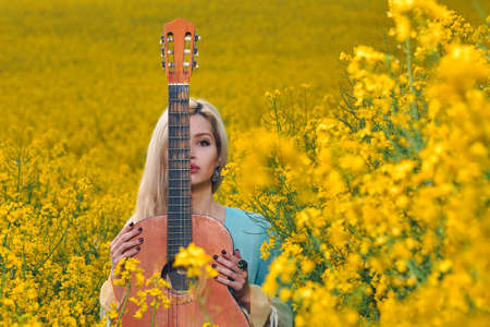 sexy woman in the field with a guitar. concept freedom, inspiration, relaxation