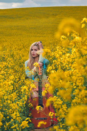 sexy woman in the field with a guitar. concept freedom, inspiration, relaxation