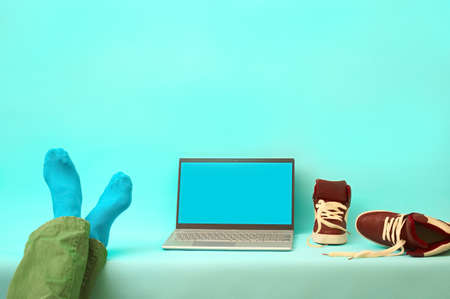 man is resting with his legs on the table. silver laptop on a blue backgroundの写真素材