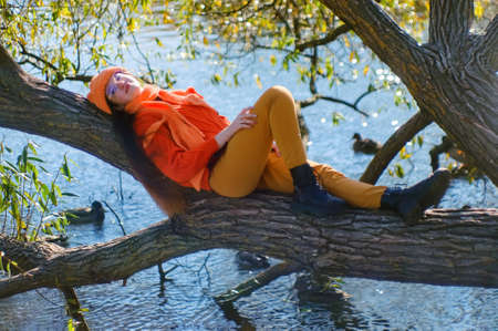 the girl lies on a tree near the reservoir. autumn portraitの写真素材