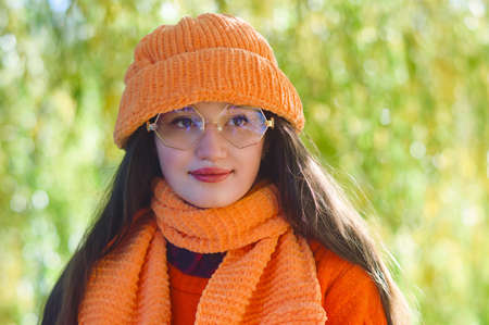 autumn portrait of a girl in glasses in an orange hat and sweater
