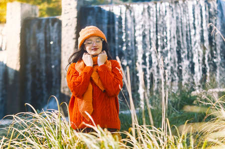 autumn portrait of a girl in glasses in an orange hat and sweaterの写真素材