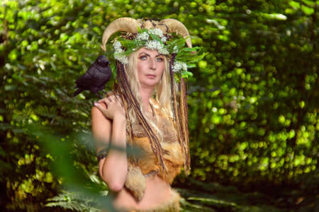Woman in the forest dressed in skins and fur. On the head of the crown from the horns. Fabulous conceptの写真素材