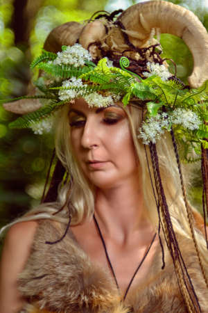 Woman in the forest dressed in skins and fur. On the head of the crown from the horns. Fabulous conceptの写真素材