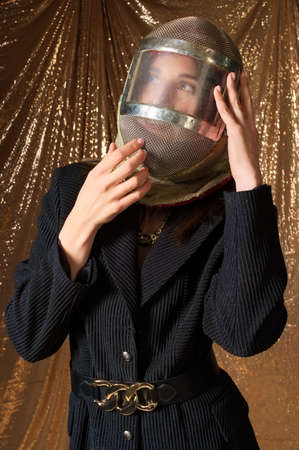 fashion portrait of a woman in a protective mask swordsman. golden backgroundの写真素材