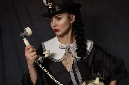 glamorous woman in a hat with bunny ears holds a retro phone in her handsの写真素材