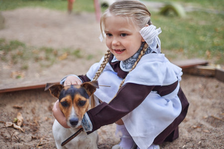 Little girl schoolgirl in uniform hugs a little dog in the yardの写真素材