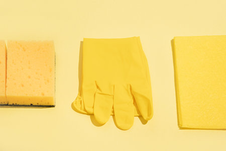 New rubber glove, foam sponge, cloth rag on a yellow background. cleaning concept.の写真素材