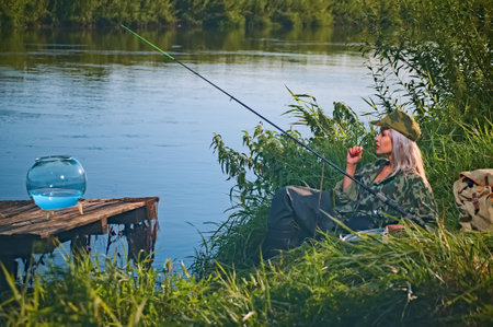 Woman fisherman catches fish on the river near the shore