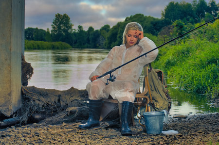 Beautiful woman fisherman is resting on the river. Female is fishing with a rod in gearの写真素材