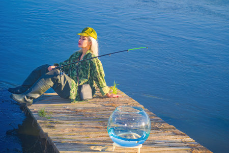 Woman fisherman fishing rod and aquarium on the bank of the river. concept.の写真素材