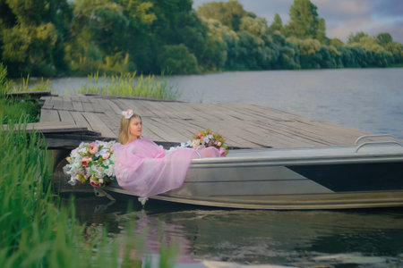A young teenage girl joyfully sits in a boat near the pier by the river, enjoying the summer breeze and the calming waters. The idyllic scenery inspires a sense of freedom and adventurer. concept inspiration. Summer.の写真素材