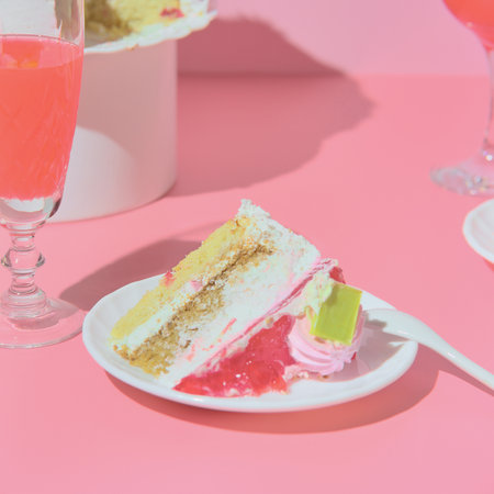 Holiday table with red wine champagne two glasses and cake. pink background.の写真素材
