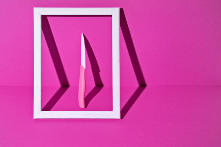 White Ceramic Knife in Photo Frame with Magenta Background. minimalist style.の写真素材