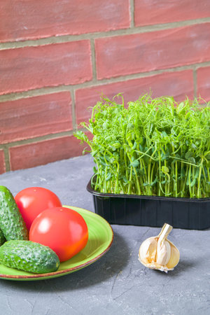 Sprouted peas in the kitchen. Fresh salad, cucumbers, tomatoes. The concept of healthy eating. brick wall background.の写真素材