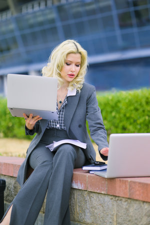 Office worker typing on two laptops outside. business concept. businesswoman at work.の写真素材