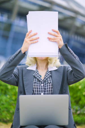 The woman covered her face with the paper. The businesswoman hid behind the paperwork. Concept.の写真素材