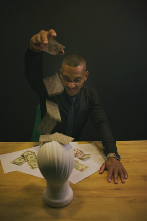 African American man playing cards at casino with mannequin head. Concept