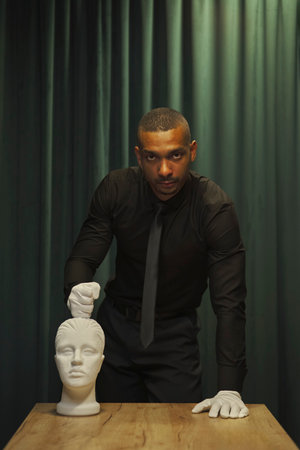 African American man holds his fist over a mannequin's head. concept green background, curtainの写真素材