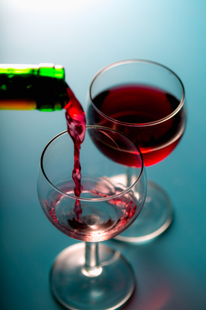 Pouring wine into the glasses, blue backgroundの写真素材