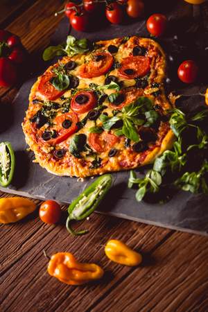 Fresh and tasty homemade pizza on wooden table with ingredientsの写真素材