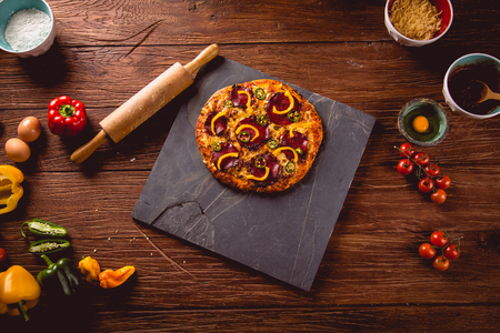 Fresh and tasty homemade pizza on wooden table with ingredientsの写真素材