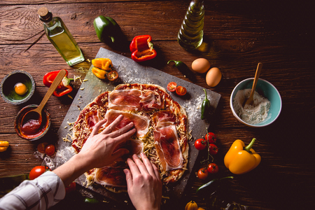 Girl is preparing homemade pizza on wooden tableの写真素材