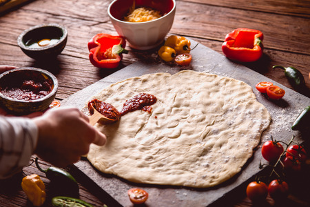 Preparing pizza with dough and tomato sauceの写真素材