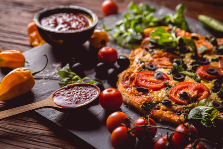 Fresh and tasty homemade pizza on wooden table with ingredientsの写真素材