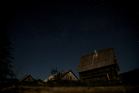 Night sky is full of stars, rural landscape with wooden villageの写真素材