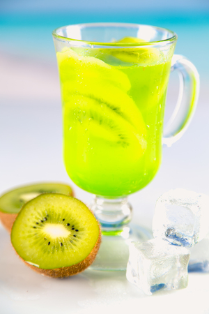 Tasty drink with kiwi on sandy beachの写真素材