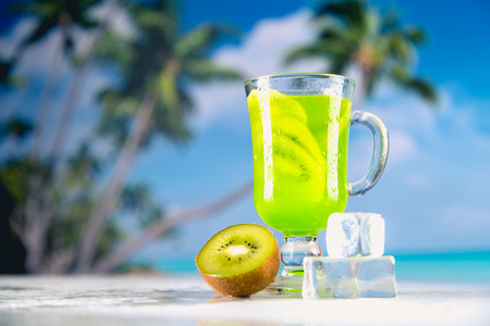 Tasty drink with kiwi on sandy beachの写真素材