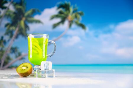 Tasty drink with kiwi on sandy beachの写真素材