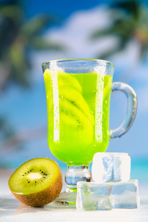 Tasty drink with kiwi on sandy beachの写真素材
