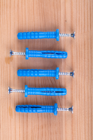 Pegs and screws on wooden table, macro shot