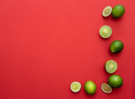 colorful slices of limes isolated on red backgroundの写真素材