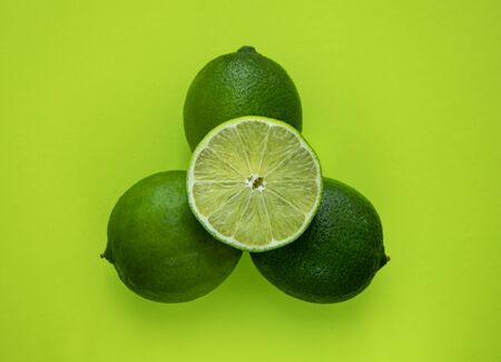 Lime slice and whole green lime isolated on green backgroundの写真素材