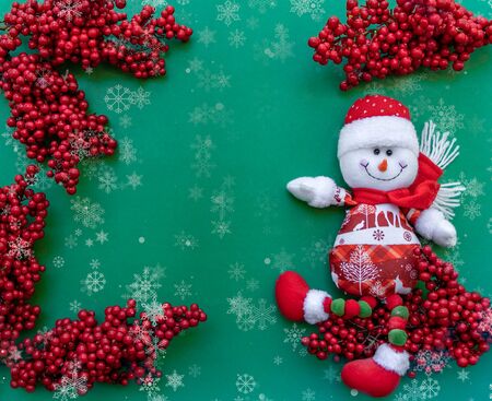 Snowman figurine on red sorb rowan branches green Christmas backgroundの写真素材