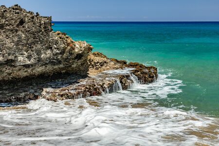Ocean foamy waves, splashes at the beach near rocksの写真素材