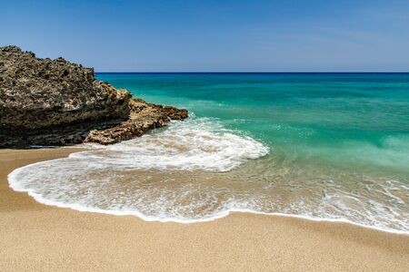 Ocean foamy waves, splashes at the beach near rocksの写真素材