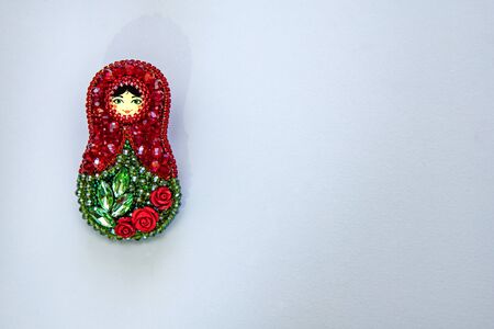 Modern fashion handmade brooch matryoshka in traditional russian style with colorful red and green beads and crystals isolated on white background, folklore and handmade concept, free space for text, border designの写真素材