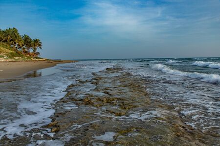 Seascape horizon with rocks in the water and ocean waves at sunrise on Cabarete beach, Dominican Republicの写真素材