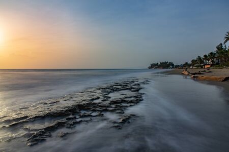 Ocean horizon with rocks sticking out of the foggy water, calm peaceful sunrise on Cabarete beach,...
