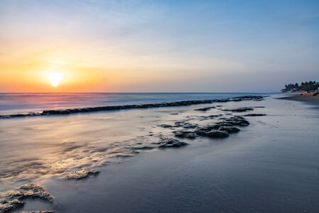 Seascape horizon with rocks in the water and ocean waves at sunrise on Cabarete beach, Dominican Republicの写真素材