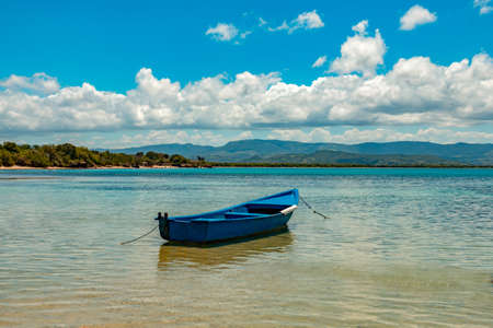 Boat in a sea bay, mountains, cloudy skyの写真素材