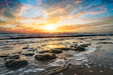 Ocean horizon with rocks sticking out of the foggy water, calm peaceful sunrise on Cabarete beach, Dominican Republicの写真素材