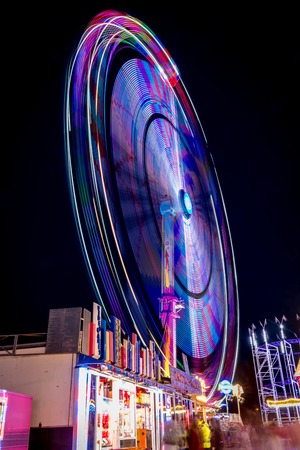 Ferris wheel shoot at night while rotating at the fair in Antwerpen, Belgium. The lights draw a colourful circle.のeditorial素材