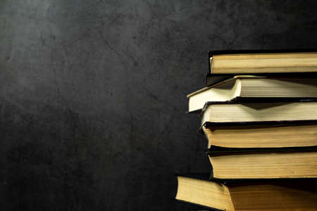 Stack of old books stacked on top of each other, collection of old books on a dark background. Side...